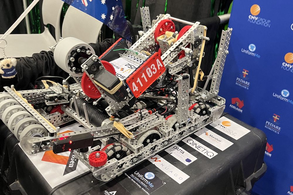 The 41103A competition robot on its case in the pit, showing the intake rollers, the drivetrain and the folding wings, with the team number plate mounted on the frame.